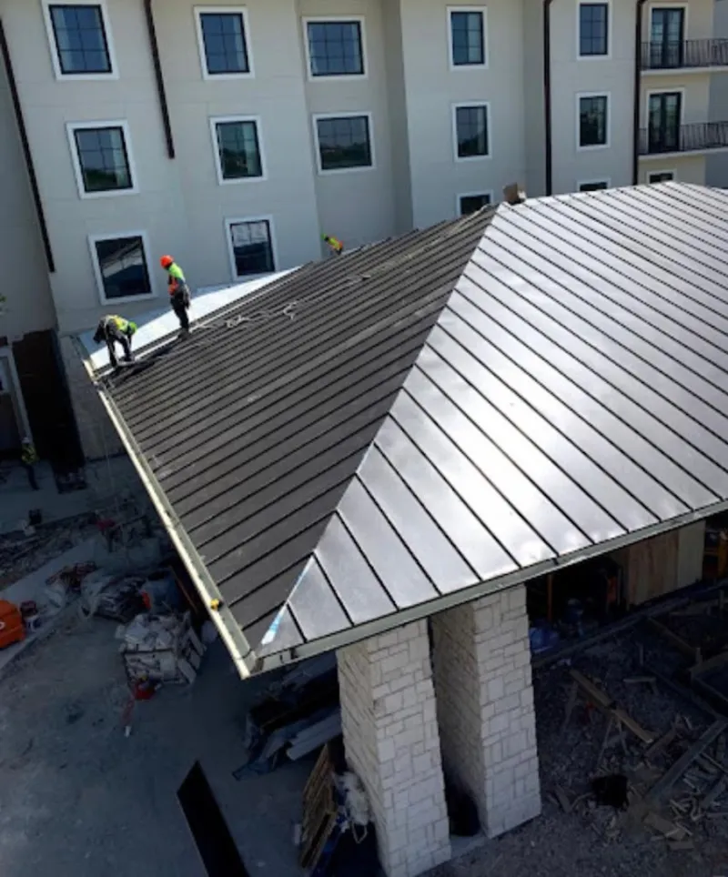 Crew installing standing seam metal roof panels on a commercial project in Estero